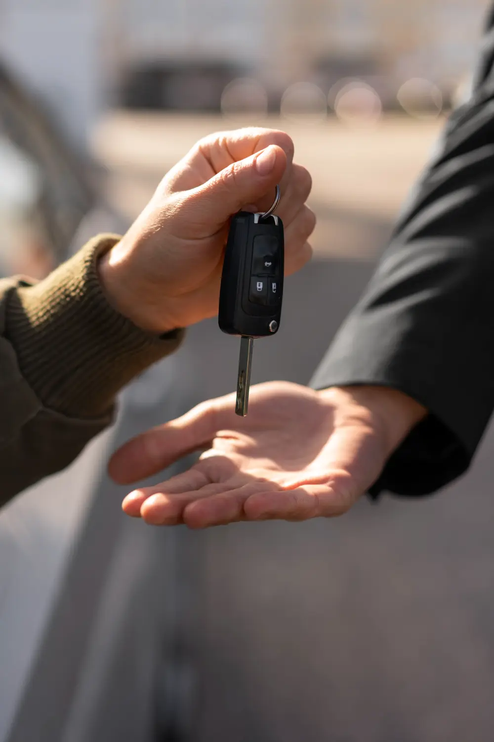 eine Person, die die Autoschlüssel an eine andere Person übergibt