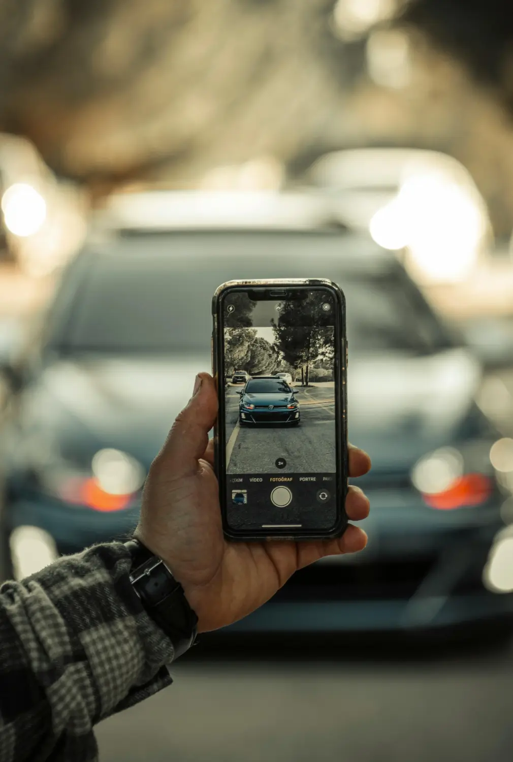 eine Person, die ein Smartphone verwendet, um ein Auto zu fotografieren
