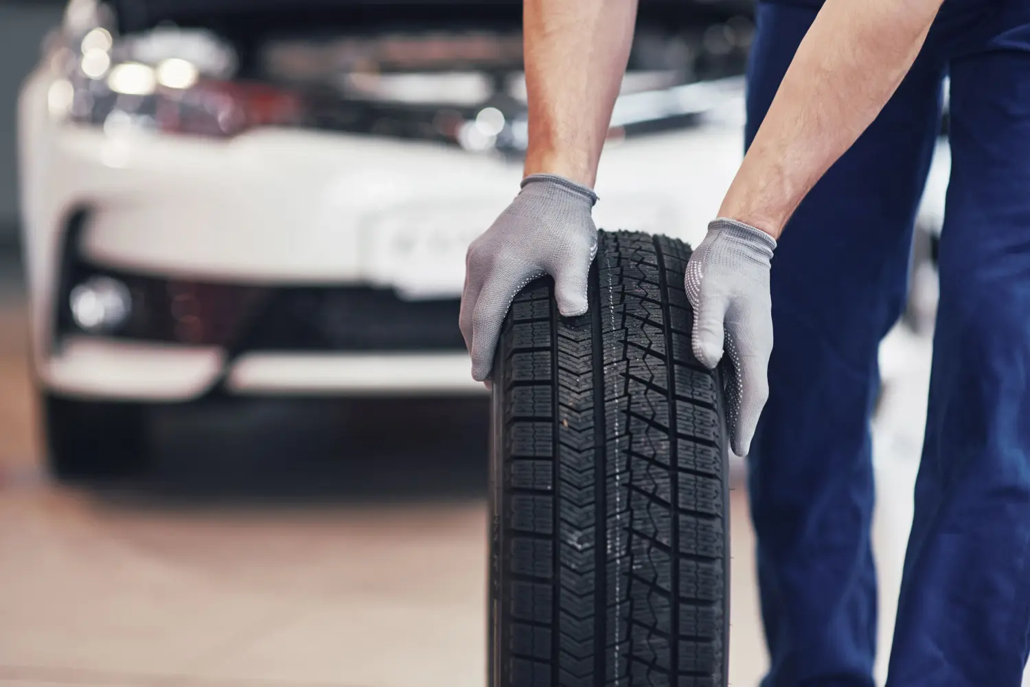 Eine Person, die einen Autoreifen in der Hand hält und das Profilmuster des Reifens hervorhebt.