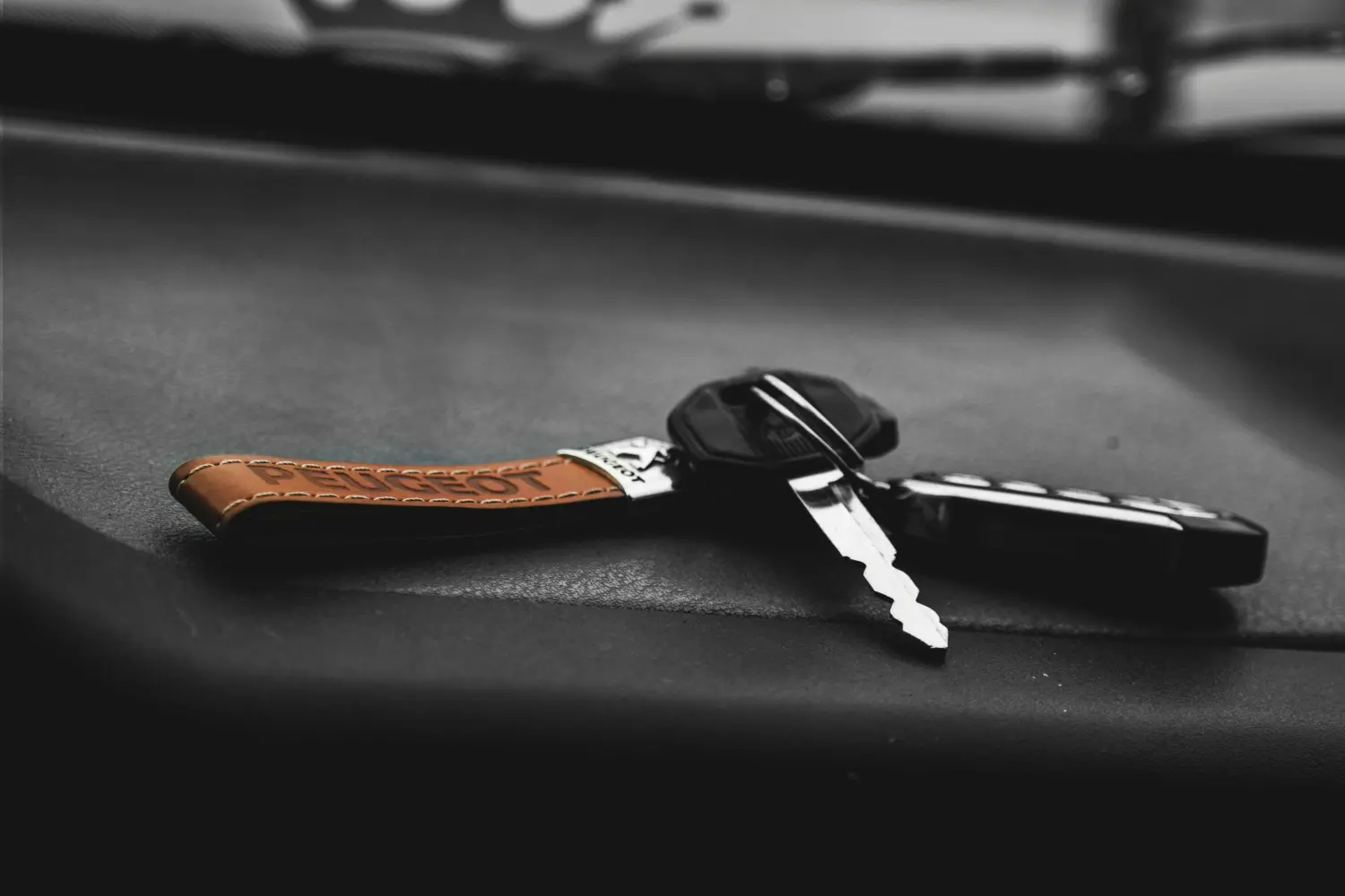 Autoschlüssel mit Schlüsselanhänger, auf einer Lederoberfläche platziert